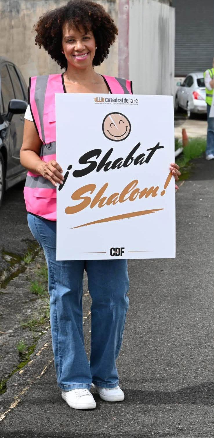 Voluntaria sonriente con un letrero que dice Shabat Shalom